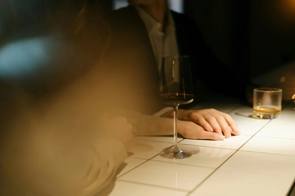 flirty couple, blurred foreground, wine on the table, presumably in a bar