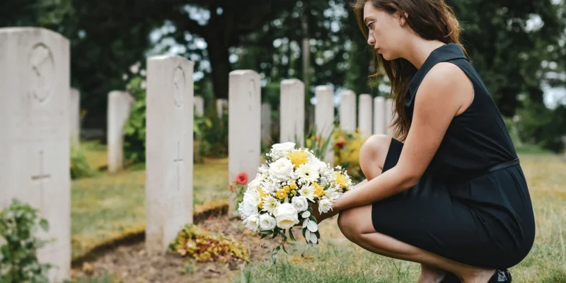 Adult woman laying flowers on grave