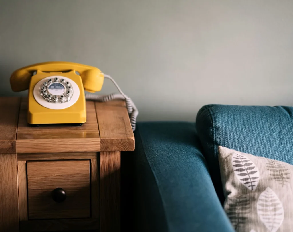 landline telephone, yellow, next to a blue sofa and throw pillow