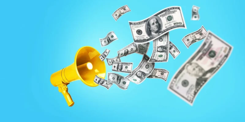 Dollar Money is flying in from the Golden yellow speaker on a blue background, a concept. Jackpot winning, creative idea. Bucks are floating. Successful business and economic development. Bonus