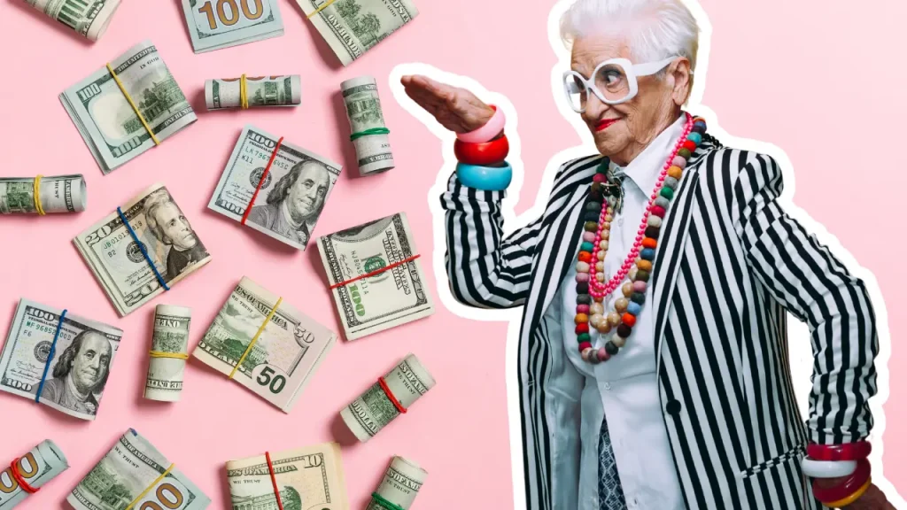 Silly senior woman dressed with lots of accessories on a pink background surround by money