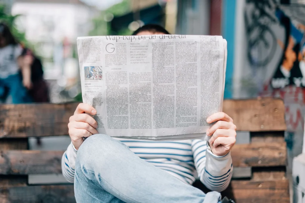 reading a newspaper on a park bench