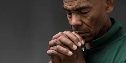 Senior man praying with hands folded, close up