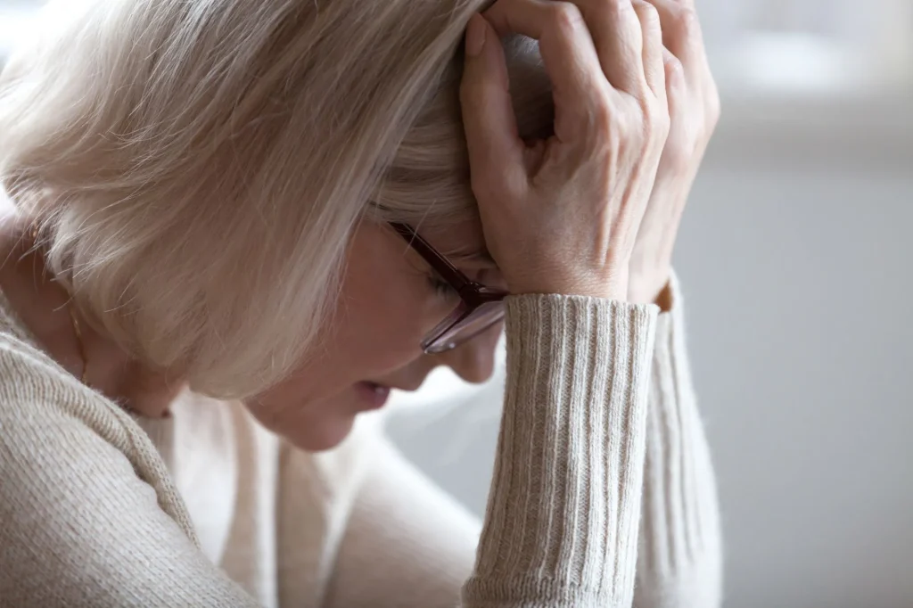 Stressed sad tired middle aged senior woman holding head in hands feeling headache migraine concept, upset old elderly mature lady in panic suffering from pain, alzheimer disease, anxiety depression, stressed and praying