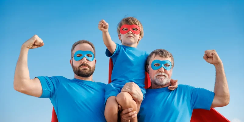 Senior, man and child outdoor against summer blue sky. Grandfather, father and son pretend to be superheroes. People having fun together.