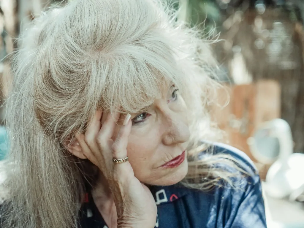 unmotivated senior woman sitting outside with head in hand
