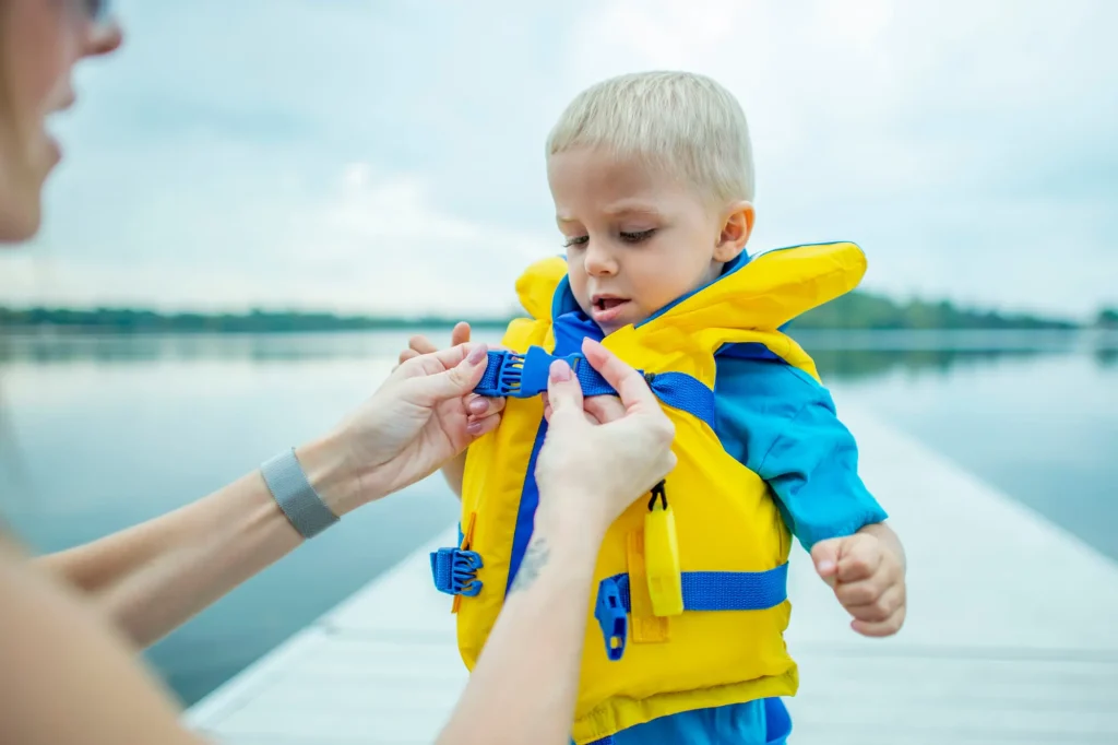 little boy putting on life vest