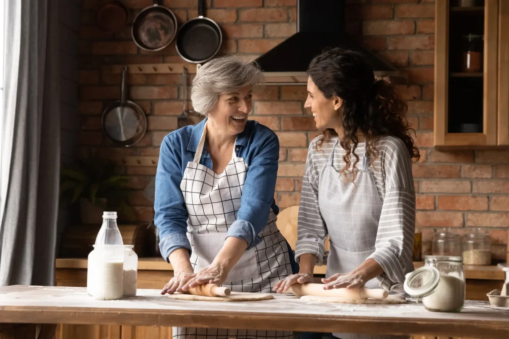 Adult daughter and older mother baking together in a kitchen