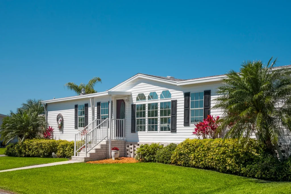 white mobile home with nice greenery and palm trees
