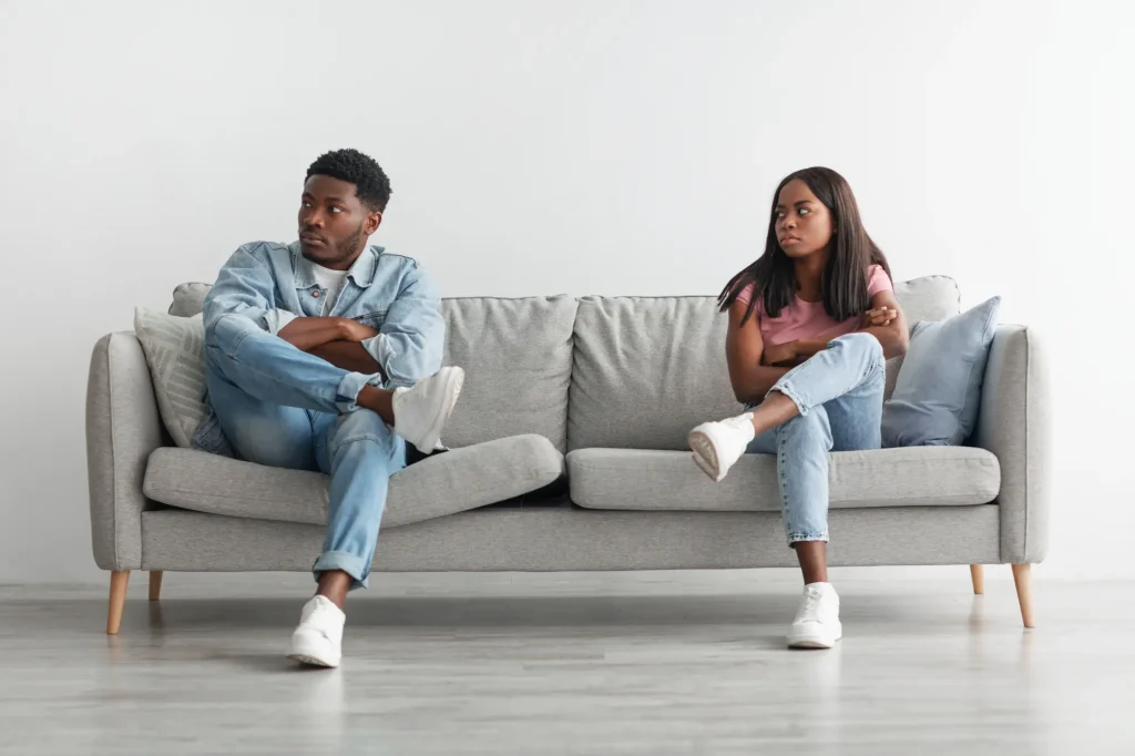 angry black couple sitting on couch, arguing
