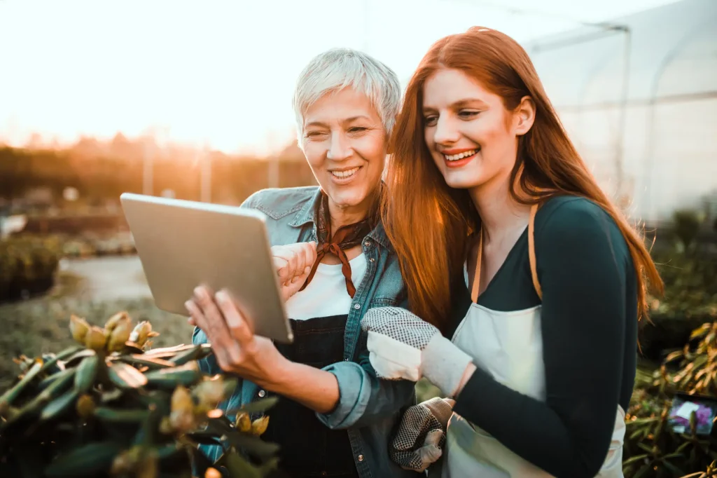 older lady and younger redhead with ipad, gardening
