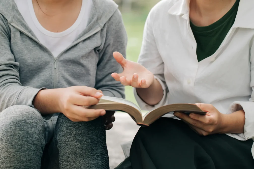 two women sitting on steps with Bible