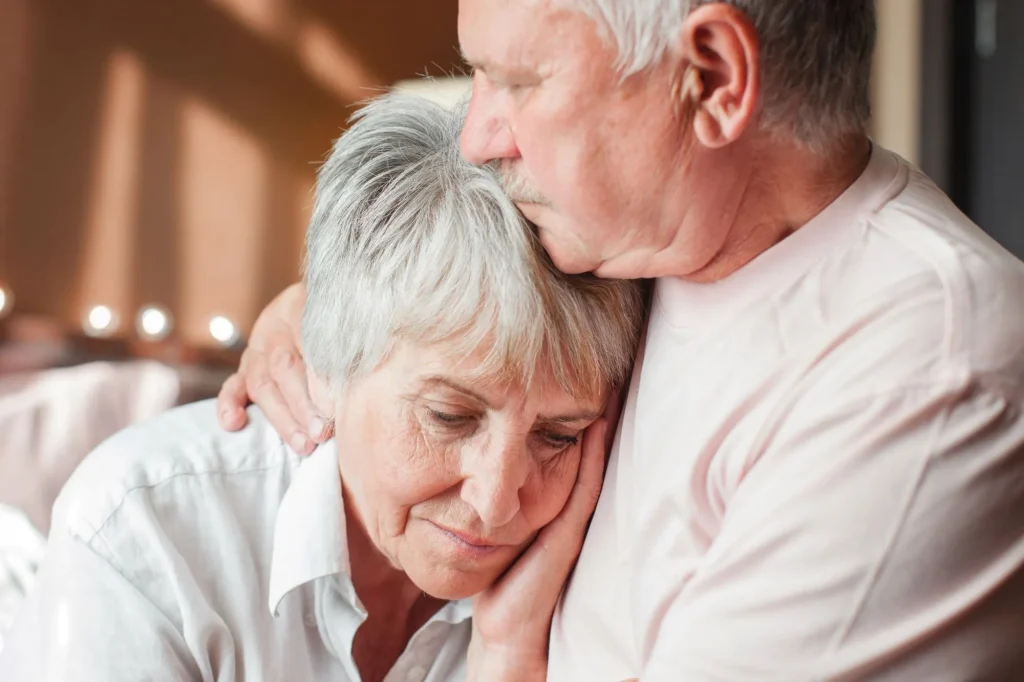 Close up mature man comforting frustrated crying woman, hugging shoulders, caring elderly husband and wife overcoming troubles, health problems, consoling and supporting, psychological help