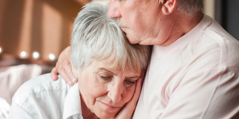Close up mature man comforting frustrated crying woman, hugging shoulders, caring elderly husband and wife overcoming troubles, health problems, consoling and supporting, psychological help