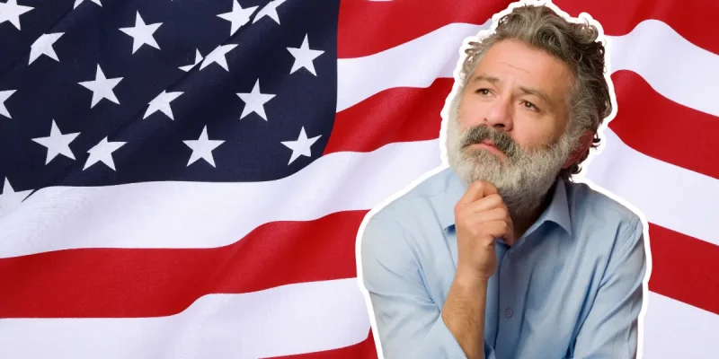 senior man with gray beard thinking in front of an American flag