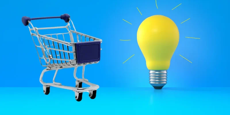 blue shopping cart on a blue background next to a yellow lightbulb