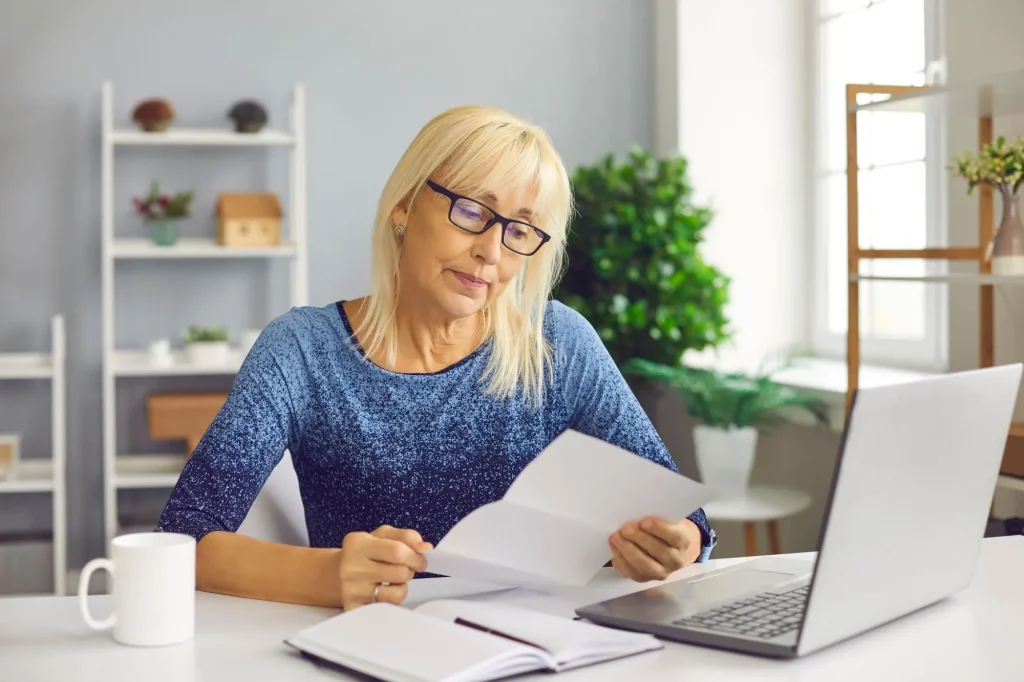 Senior lady receiving document with bad news. Serious woman looking at huge domestic utility bill, high taxes or negative bank account balance notification
