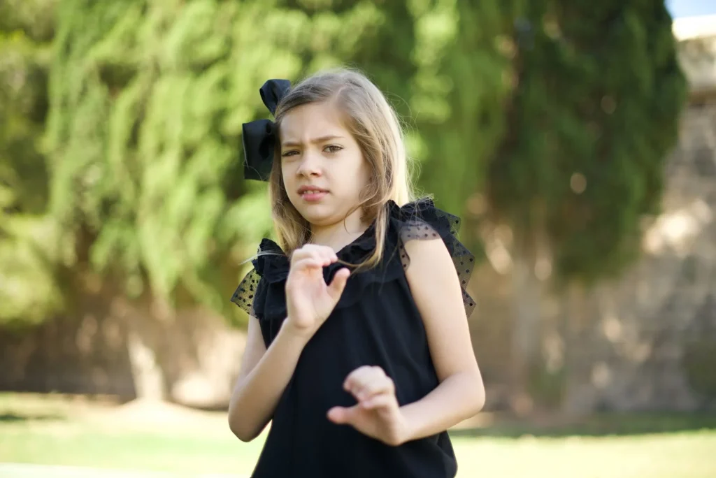  Displeased little girl standing outdoors dressed casual, says fie and has dissatisfied facial expression