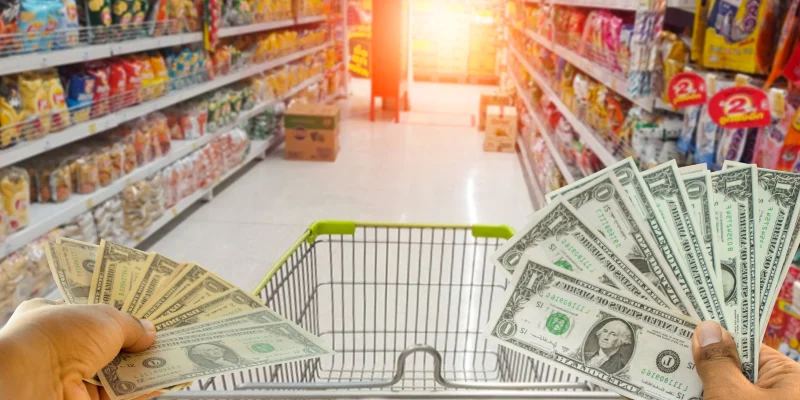 A hand holding dollars on shop. A man holding dollars for cash on product background.Money for sales exchange. Photo concept finances and money.