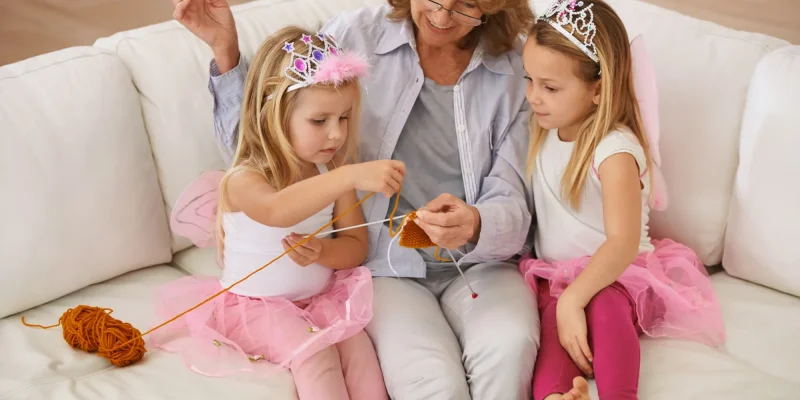 grandchildren dressed like princesses sitting on couch with grandmother