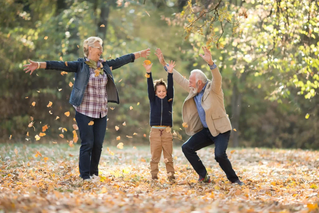 grandparents with grandson in leaves