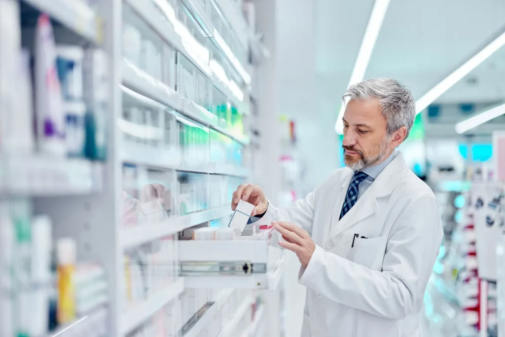 Serious-looking man, pharmacist, taking a medicine from the drawer.