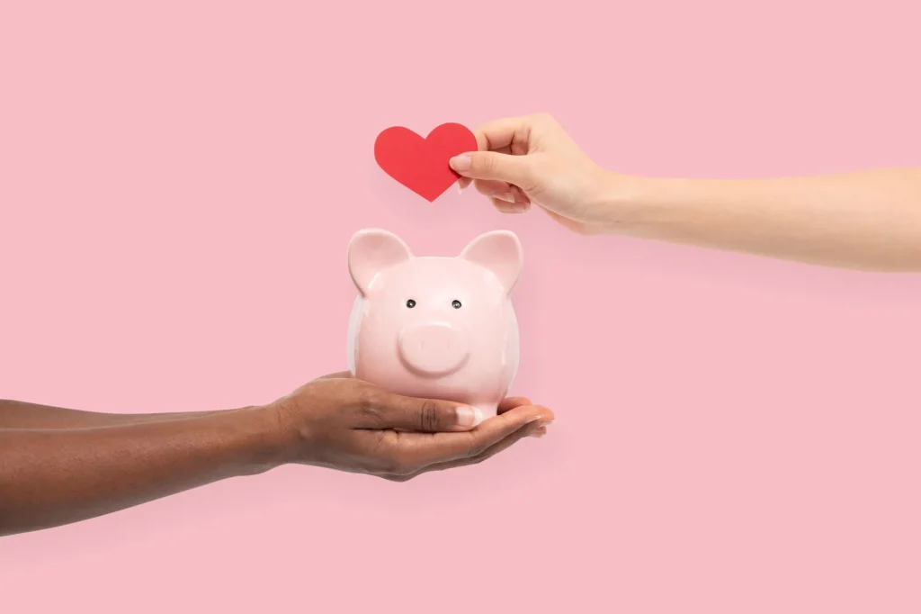 piggy bank with hearts and hands symbolizing charity