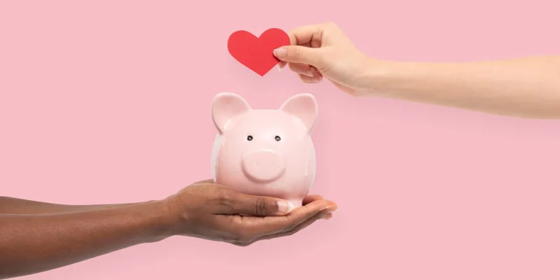 piggy bank with hearts and hands symbolizing charity