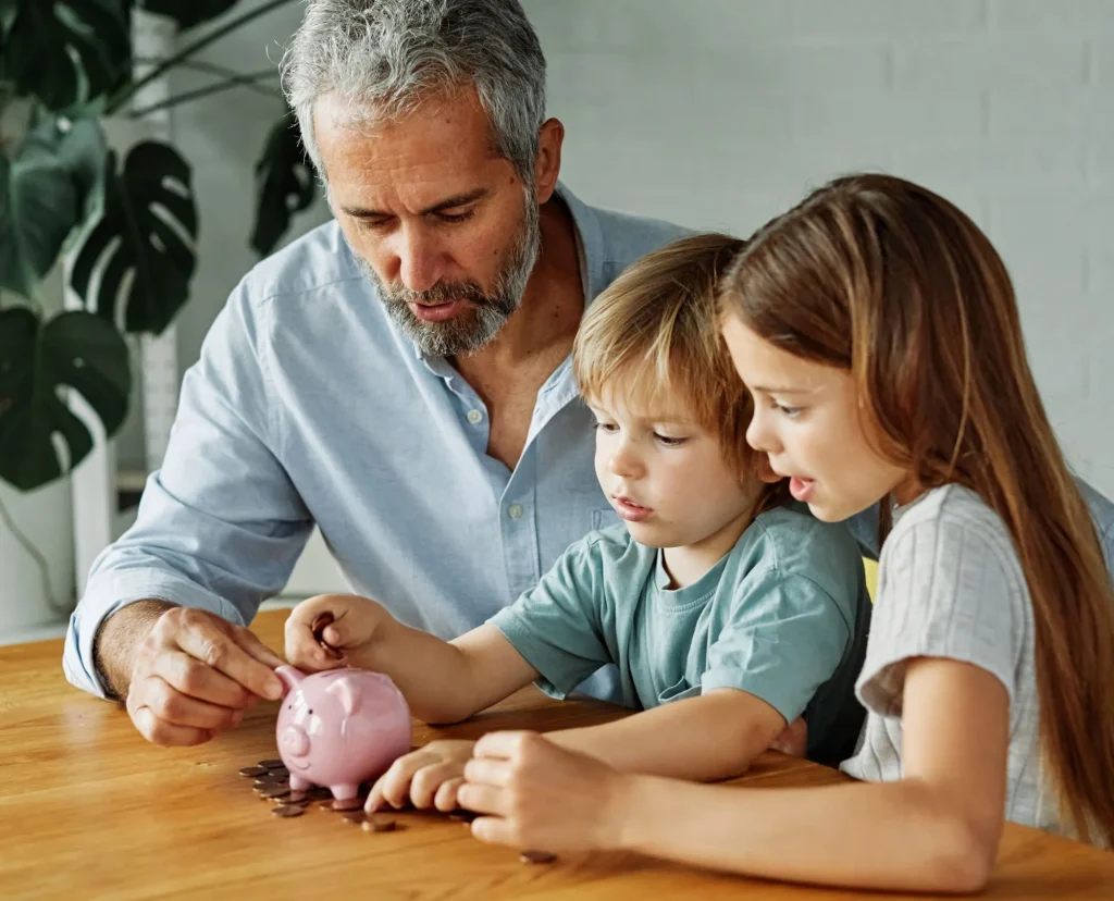 grandfather helping grandchildren learn saving and investing with a piggy bank