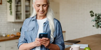 senior woman with long gray hair smiling and dialing a phone