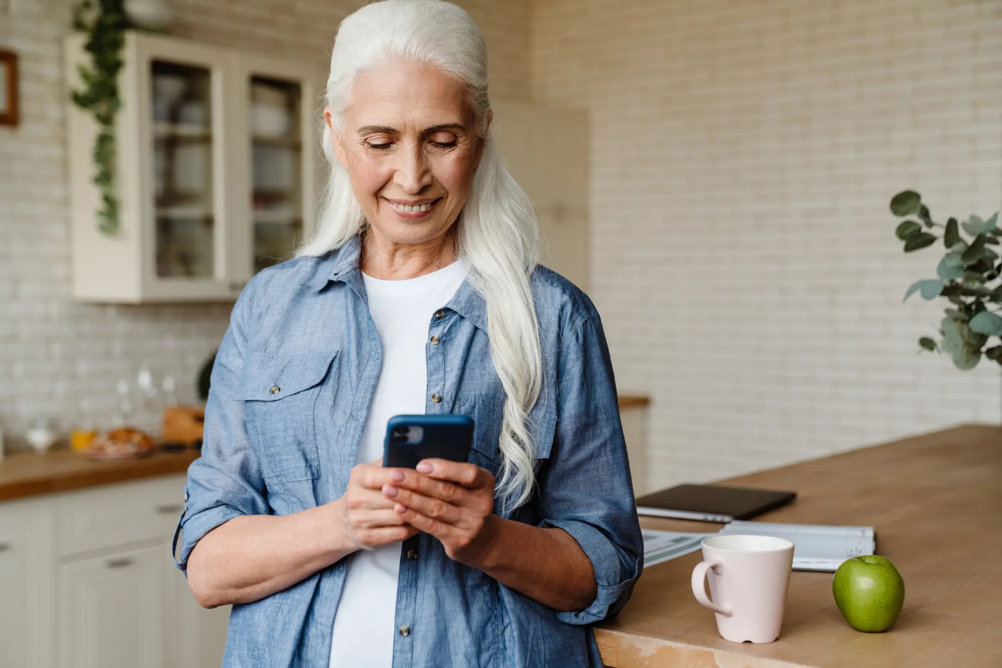 senior woman with long gray hair smiling and dialing a phone