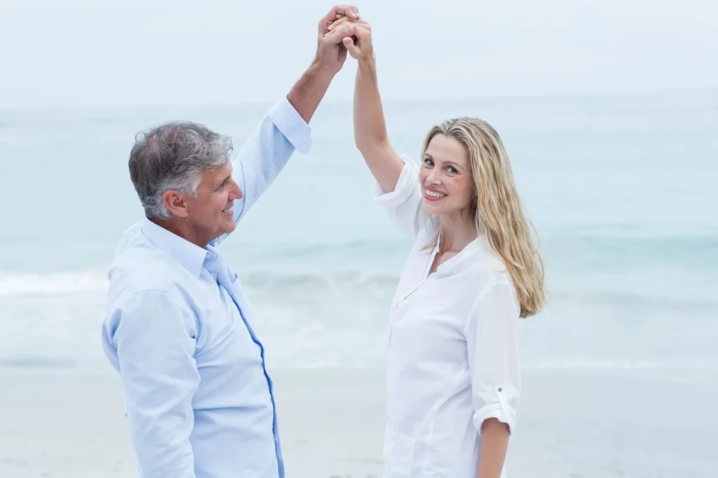 two retirees dancing on a beach