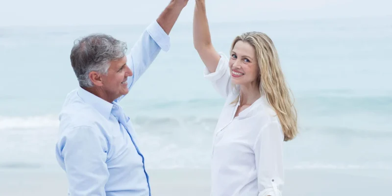 two retirees dancing on a beach