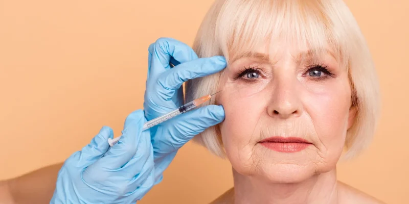Close up photo beautiful amazing mature she her aged lady surgeon medic touch hold hands arms getting facial skin hyaluronic cosmetology injecting facelift nude isolated pastel beige background