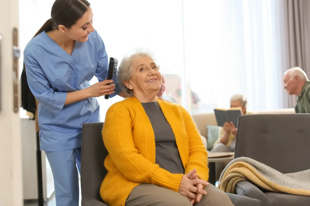 nurse brushing an elderly woman in a mustard yellow sweater's hair