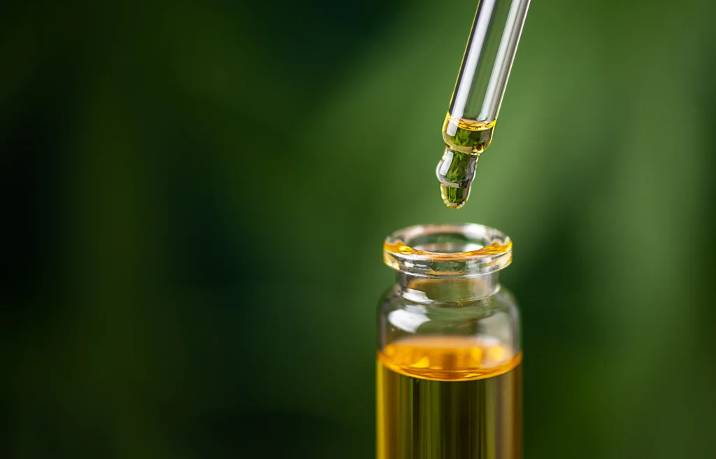 essential oil close up with green leaves blurred in background