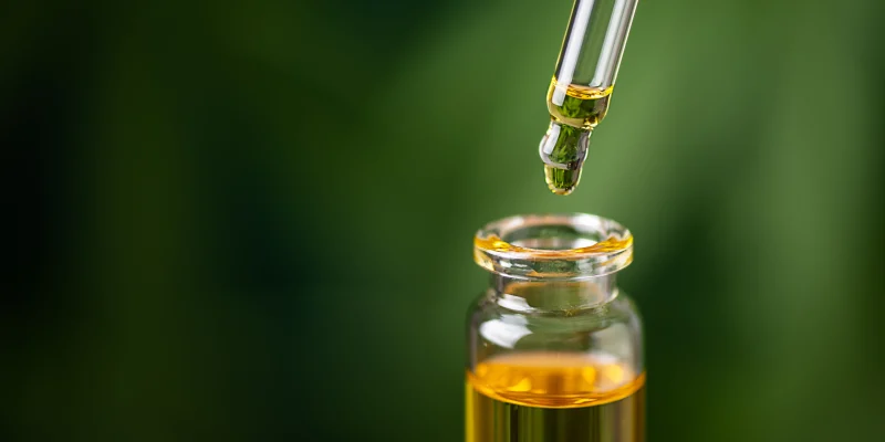 essential oil close up with green leaves blurred in background