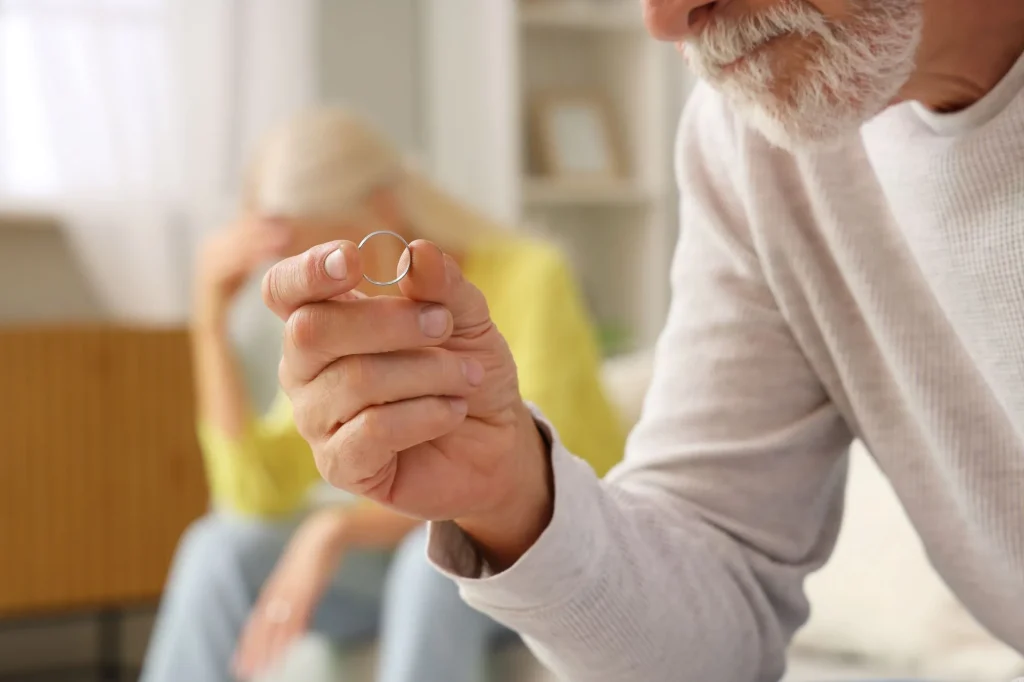 Mature man with taken wedding ring at home, closeup. Divorce concept