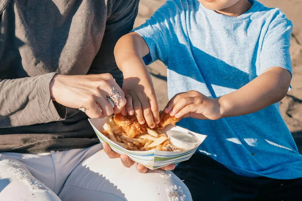 child and adult having an outdoor meal