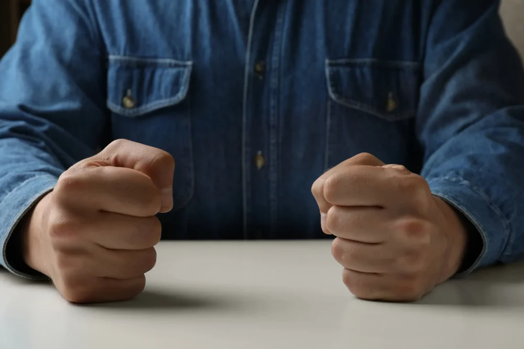 fists clenched on table