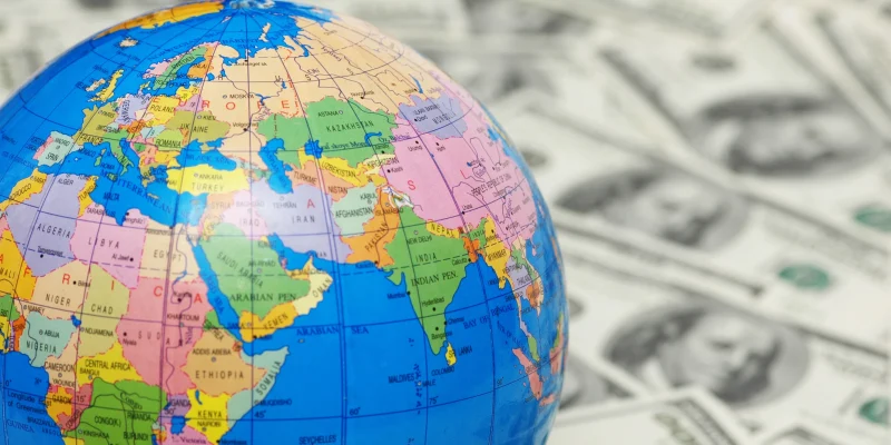 world globe in foreground and out of focus money in the background