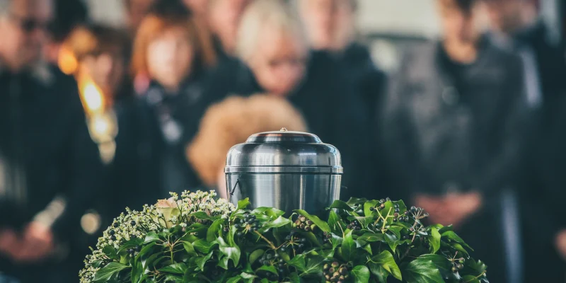 metal urn cremation with funeral in the background blurred