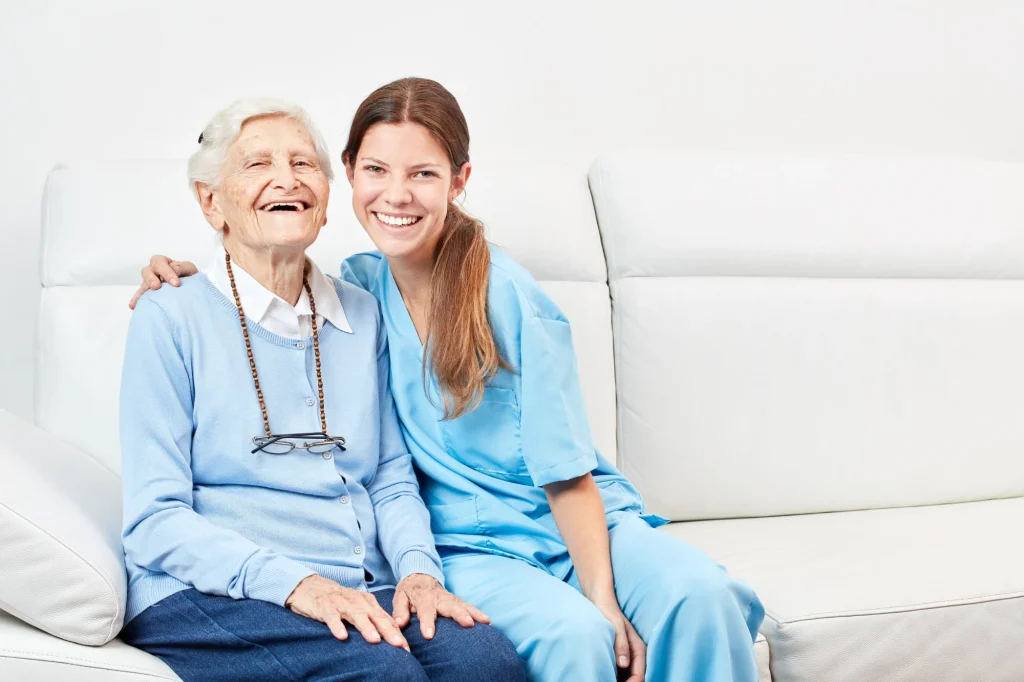 nurse and senior woman on couch smiliing