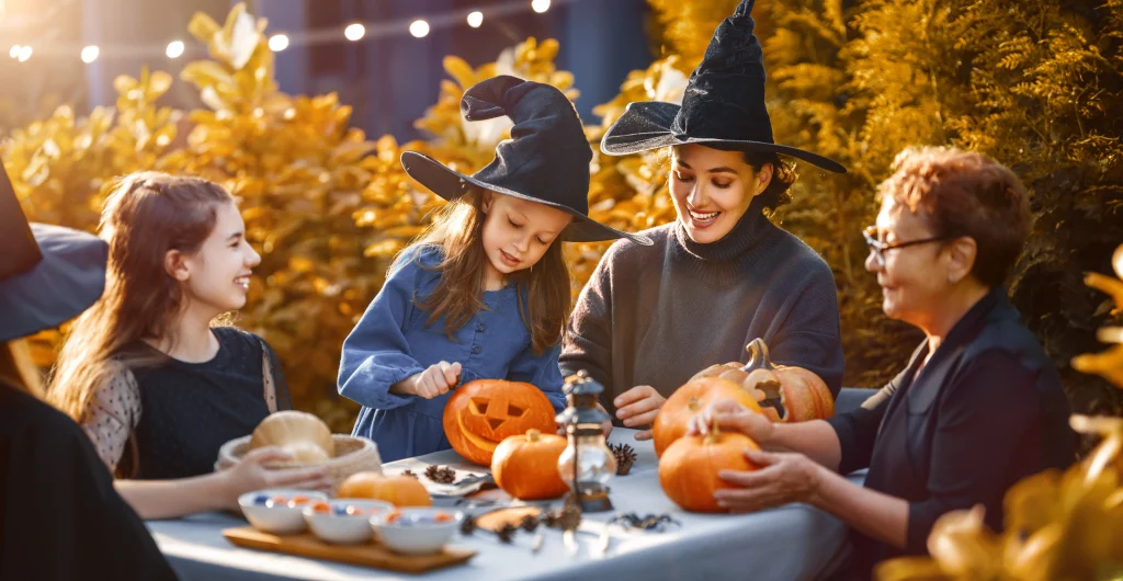 Happy family preparing for Halloween. Mother, grandmother and children carving pumpkins in the backyard of the house