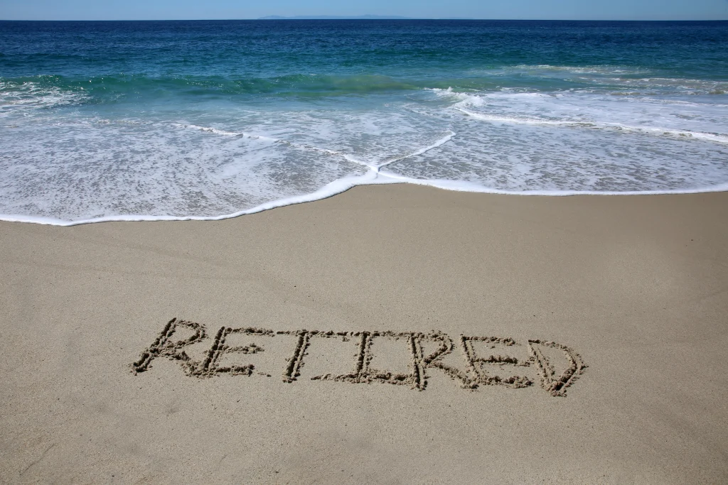 Words written in sand. The word RETIRED written in the sand on the beach with the ocean in the background
