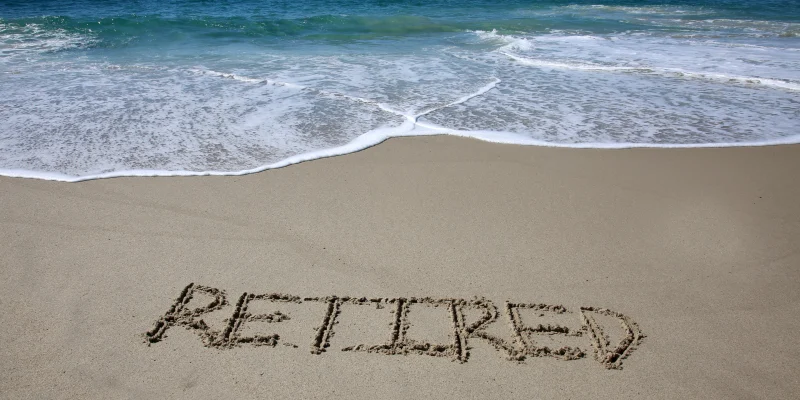 Words written in sand. The word RETIRED written in the sand on the beach with the ocean in the background