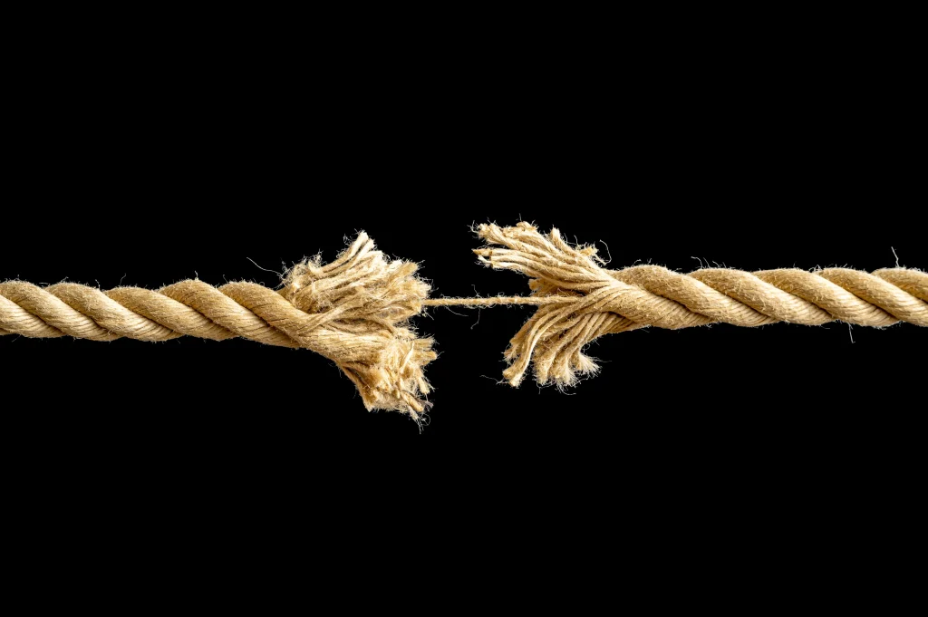 black background with a rope in the foreground that is experiencing stress and about to break from tension
