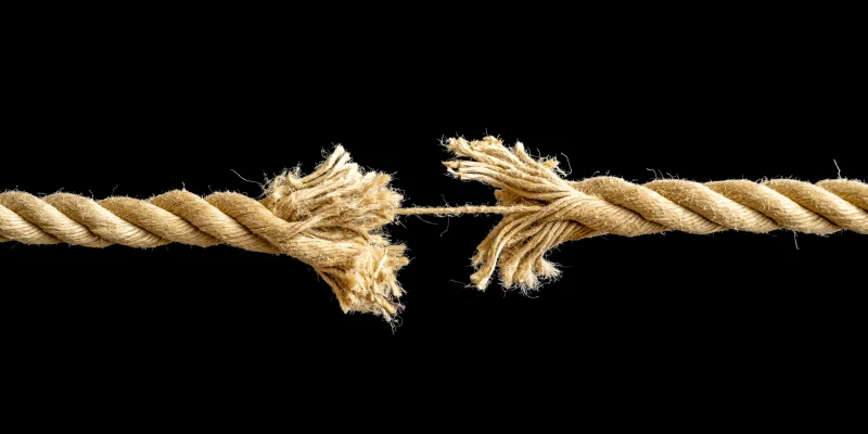 black background with a rope in the foreground that is experiencing stress and about to break from tension