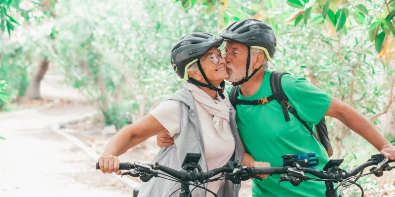 Couple of cute and sweet seniors in love enjoying together nature outdoors having fun with bikes