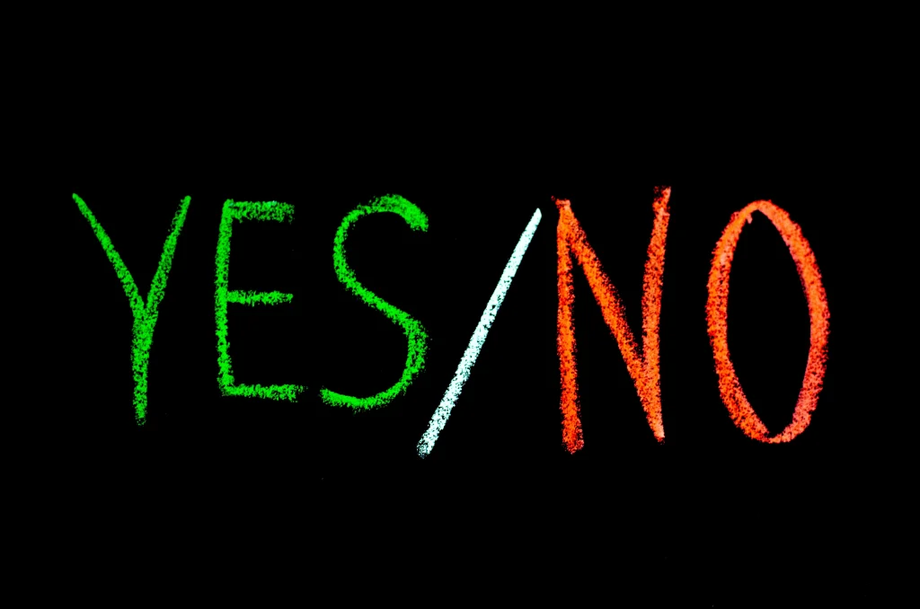 yes or no written in green and red chalk on a black background